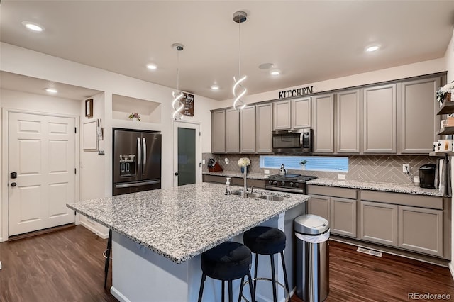 kitchen featuring gray cabinetry, dark wood-type flooring, a kitchen breakfast bar, appliances with stainless steel finishes, and a sink