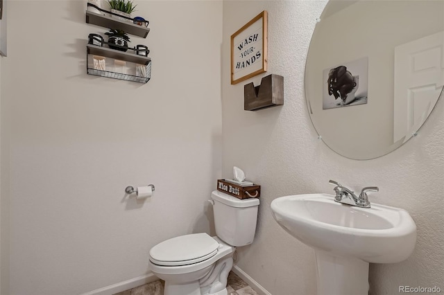 half bathroom featuring baseboards and toilet