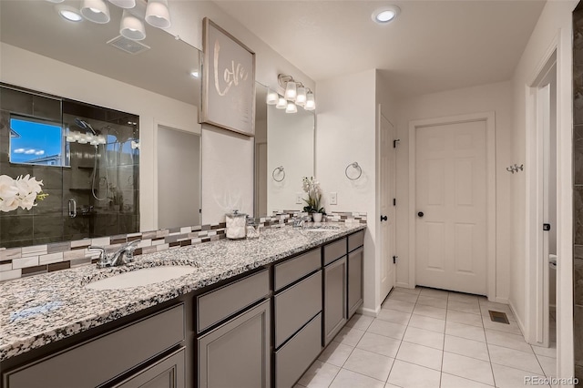 bathroom with double vanity, visible vents, a stall shower, and a sink