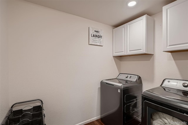 clothes washing area featuring washing machine and dryer, cabinet space, and baseboards