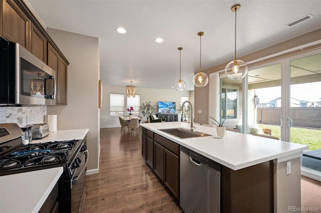 kitchen with sink, an island with sink, dark brown cabinets, and appliances with stainless steel finishes