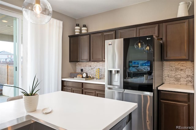 kitchen with decorative backsplash, stainless steel fridge, dark brown cabinetry, and decorative light fixtures