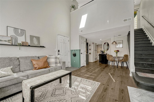 living room with wood-type flooring and a towering ceiling