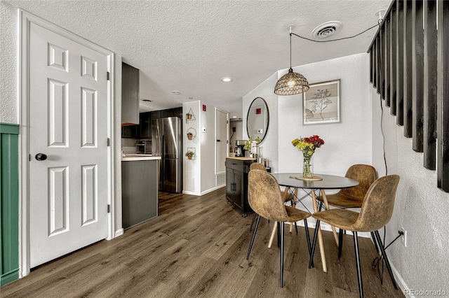 dining room with a textured ceiling and dark wood-type flooring