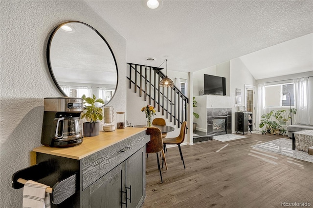 interior space with wood counters, lofted ceiling, a fireplace, a textured ceiling, and wood-type flooring