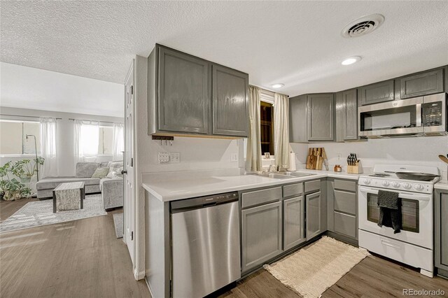 kitchen featuring gray cabinetry, dark hardwood / wood-style floors, a textured ceiling, and appliances with stainless steel finishes