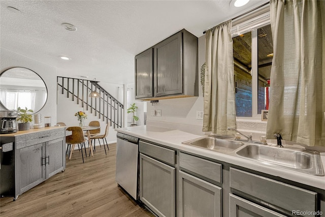 kitchen featuring gray cabinetry, dishwasher, sink, light hardwood / wood-style flooring, and a textured ceiling