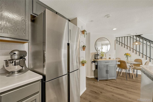 970 S Dawson Way Unit 10, Aurora, CO 80012 - kitchen featuring appliances with stainless steel finishes, gray cabinetry, light wood-style floors, a textured ceiling, and light countertops
