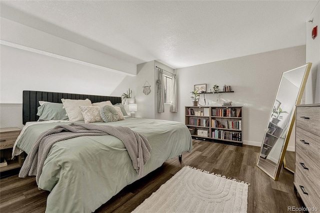 bedroom with a textured ceiling, vaulted ceiling with beams, and dark wood-type flooring