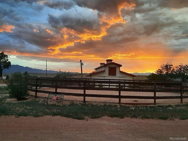 895 B St, Penrose, CO 81240 - yard at dusk featuring a barn, fence, an outdoor structure, a mountain view, and a view of rural / pastoral area