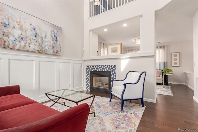 living area with a tiled fireplace, a decorative wall, recessed lighting, and wood finished floors