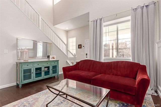 living area featuring stairs, baseboards, and dark wood-style flooring