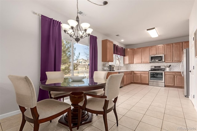 kitchen featuring light tile patterned floors, decorative backsplash, an inviting chandelier, stainless steel appliances, and a sink