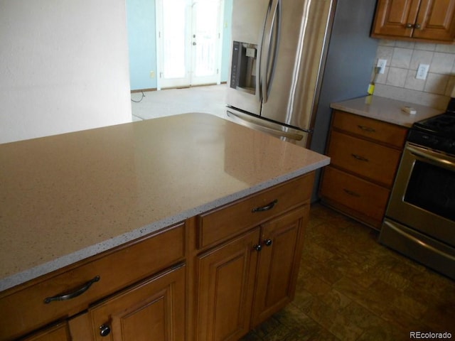 kitchen with light stone countertops, backsplash, and stainless steel appliances