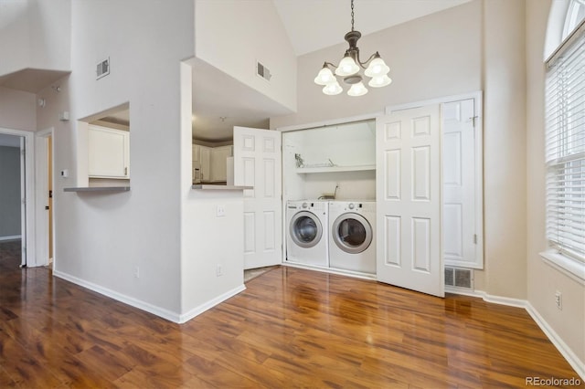 laundry area featuring washing machine and clothes dryer, laundry area, a notable chandelier, a towering ceiling, and visible vents