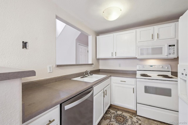kitchen with a sink, a textured wall, white cabinets, and white appliances