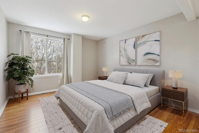 bedroom with baseboards, light wood finished floors, and visible vents
