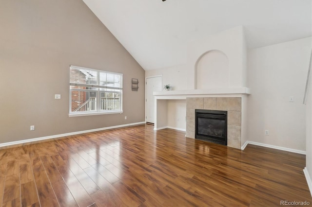 unfurnished living room featuring high vaulted ceiling, baseboards, a fireplace, and wood finished floors