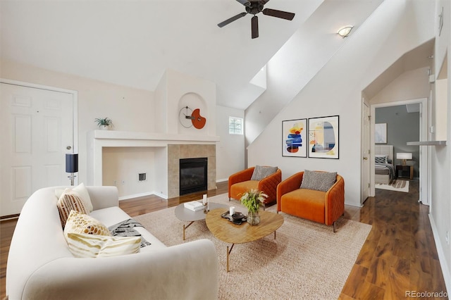 living area with ceiling fan, a fireplace, wood finished floors, baseboards, and lofted ceiling