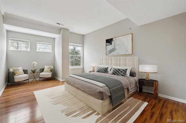 bedroom with baseboards, wood finished floors, and visible vents
