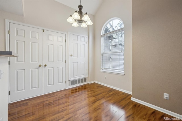 unfurnished dining area with visible vents, wood finished floors, baseboards, a notable chandelier, and lofted ceiling