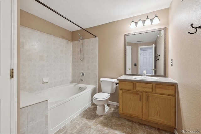 bathroom with a textured wall, vanity, toilet, baseboards, and shower / washtub combination
