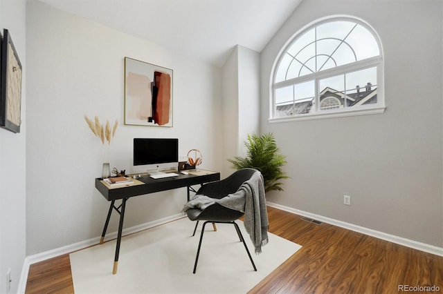 home office featuring baseboards, lofted ceiling, wood finished floors, and visible vents