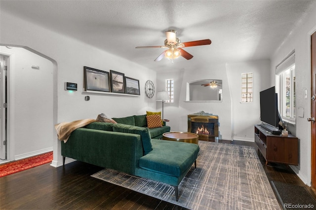 living room with dark hardwood / wood-style floors, a textured ceiling, and ceiling fan