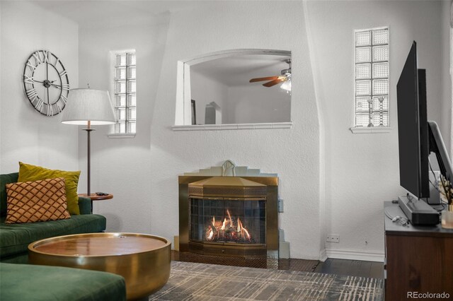 living area featuring ceiling fan and dark hardwood / wood-style flooring