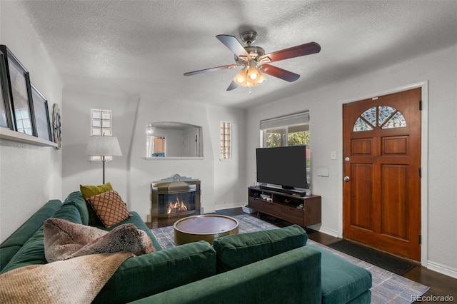 living room featuring a textured ceiling, ceiling fan, and dark hardwood / wood-style flooring