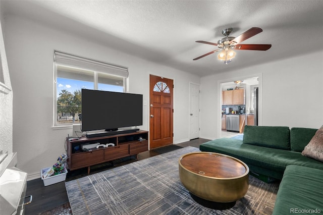 living room featuring ceiling fan, dark wood-type flooring, and a textured ceiling