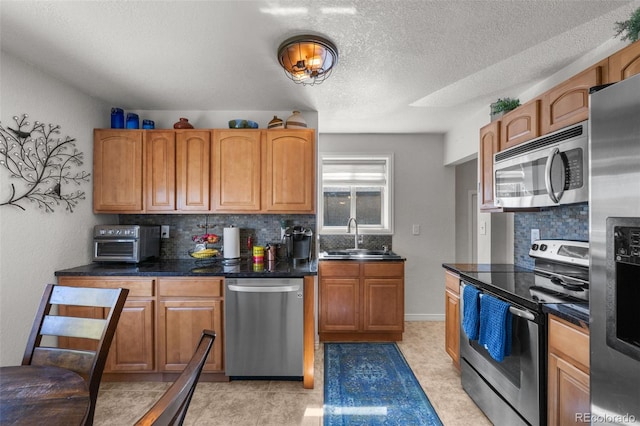 kitchen featuring decorative backsplash, appliances with stainless steel finishes, sink, and a textured ceiling