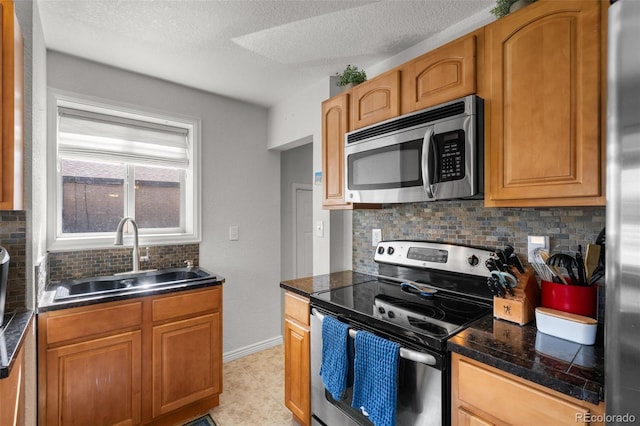 kitchen with appliances with stainless steel finishes, tasteful backsplash, sink, and a textured ceiling