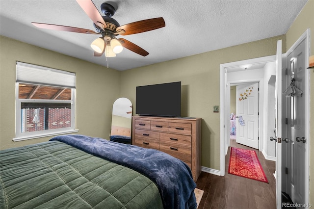 bedroom with ceiling fan, a textured ceiling, and dark wood-type flooring