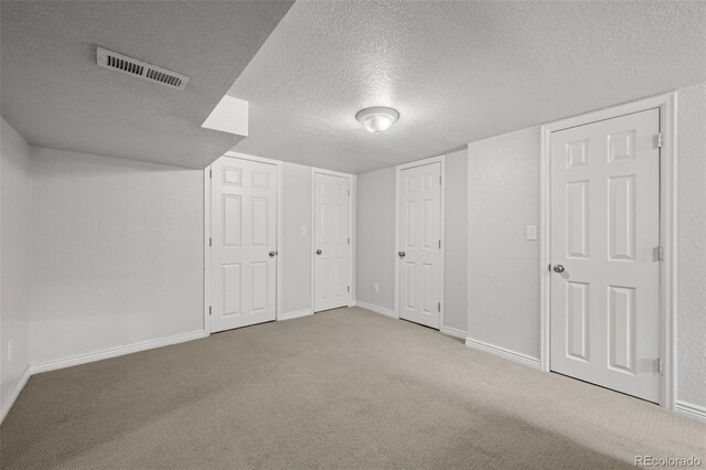 additional living space with light carpet and a textured ceiling