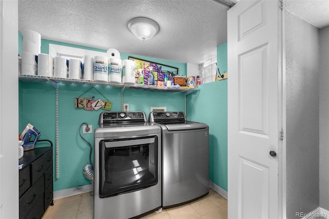 clothes washing area with independent washer and dryer, light tile patterned floors, and a textured ceiling