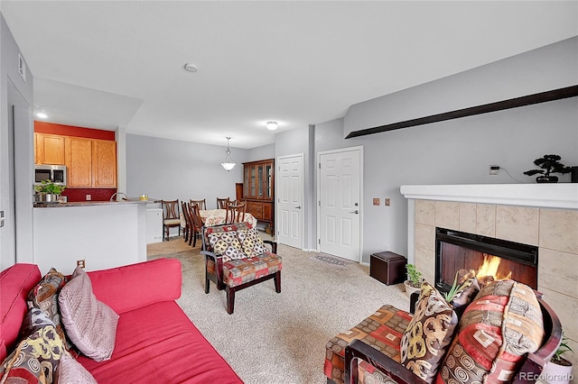 living area with light colored carpet, visible vents, and a tiled fireplace