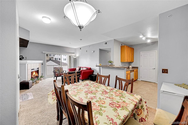 dining space featuring a tiled fireplace and visible vents