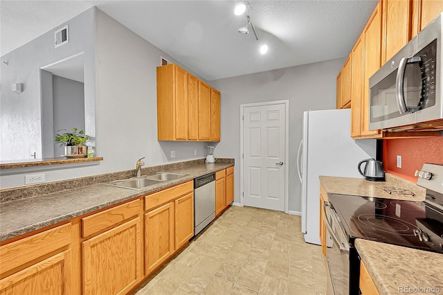 kitchen with dark countertops, visible vents, appliances with stainless steel finishes, a sink, and a textured ceiling