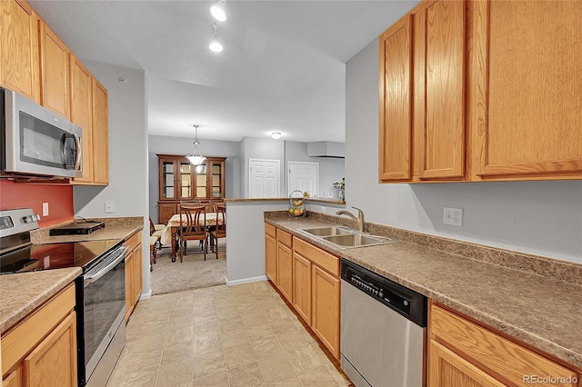 kitchen with appliances with stainless steel finishes, a sink, hanging light fixtures, and baseboards