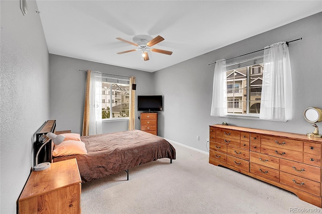 bedroom featuring a ceiling fan, light colored carpet, and baseboards