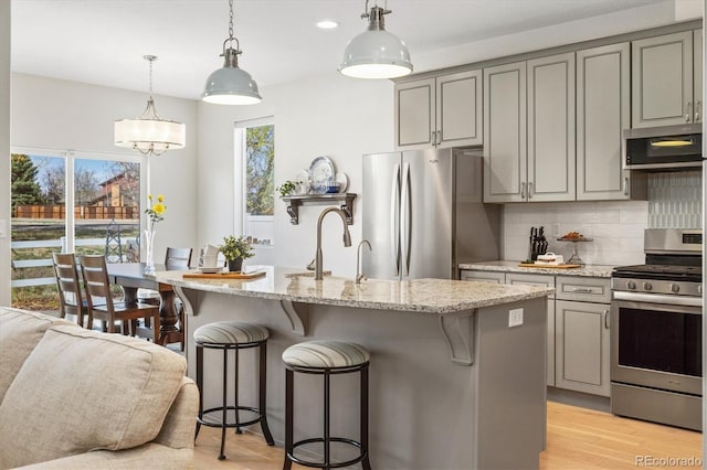 kitchen with tasteful backsplash, gray cabinets, appliances with stainless steel finishes, and a breakfast bar