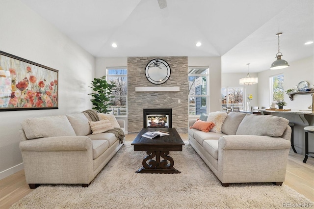 863 Shirttail Peak Dr, Windsor, CO 80550 - living area with light wood-type flooring, lofted ceiling, a multi sided fireplace, recessed lighting, and a chandelier