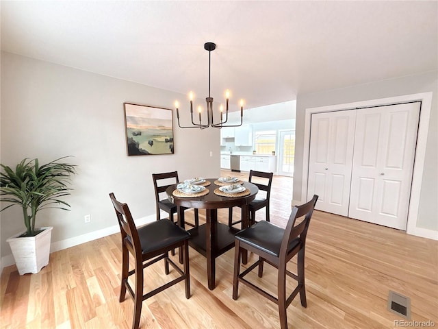 dining room featuring light wood-type flooring, an inviting chandelier, baseboards, and visible vents