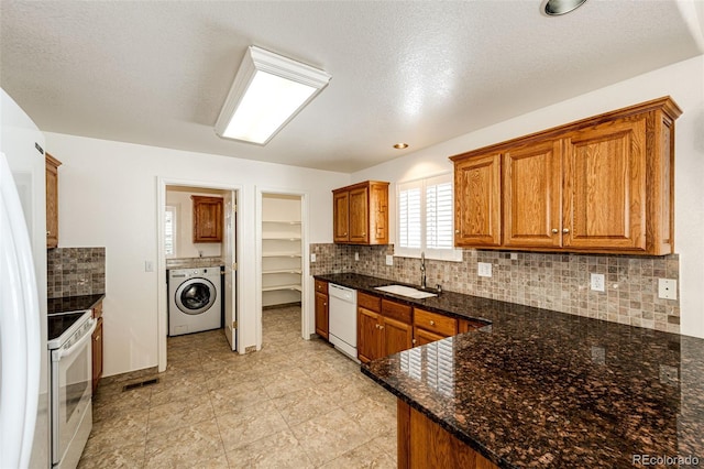 kitchen with white appliances, dark stone counters, sink, a textured ceiling, and washer / dryer