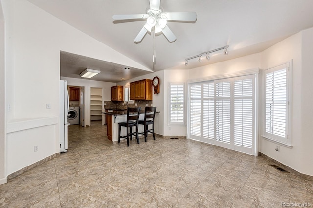 kitchen with a breakfast bar area, ceiling fan, a healthy amount of sunlight, and vaulted ceiling