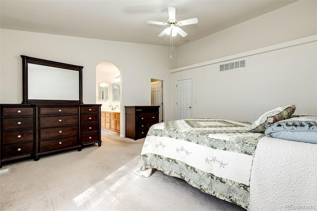 bedroom with light carpet, connected bathroom, vaulted ceiling, and ceiling fan