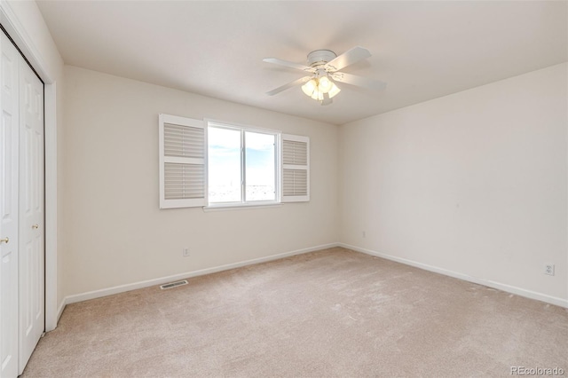 unfurnished bedroom featuring a closet, light colored carpet, and ceiling fan