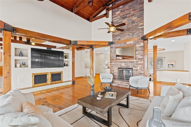 living room featuring built in features, a fireplace, wood ceiling, beam ceiling, and light hardwood / wood-style flooring