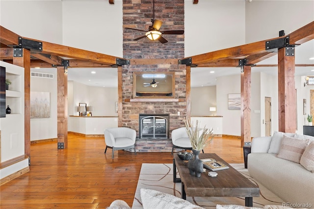 living room with ceiling fan, a large fireplace, and light hardwood / wood-style floors